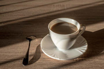 cup of morning latte coffee with saucer and spoon on the table
