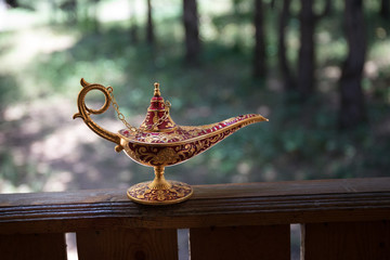 Antique artisanal Aladdin Arabian nights genie style oil lamp at the forest. Lamp of wishes fantasy...