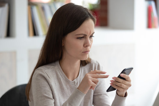 Frowny face young woman holding smartphone read unpleasant message