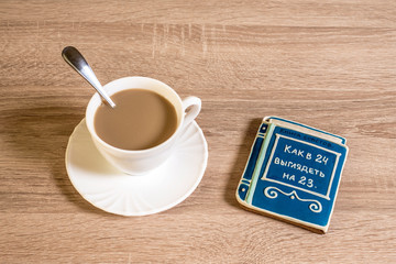 cup of morning coffee latte on a table with cookies in the form of a small book