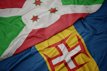 waving colorful flag of madeira and national flag of burundi .