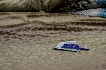 open condom packaging lies on the bed