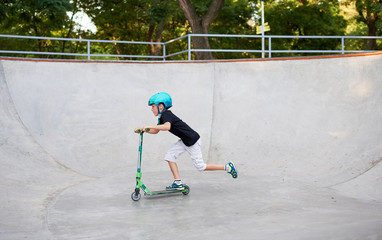 A boy on a scooter and in protective helmet do incredible stunts in skate park. Extreme jump. The...