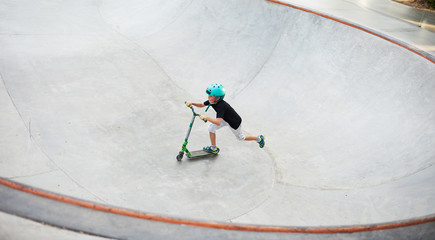 A boy on a scooter and in protective helmet do incredible stunts in skate park. Extreme jump. The concept of a healthy lifestyle and sports leisure © oes