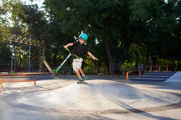 A boy on a scooter and in protective helmet do incredible stunts in skate park. Extreme jump. The concept of a healthy lifestyle and sports leisure