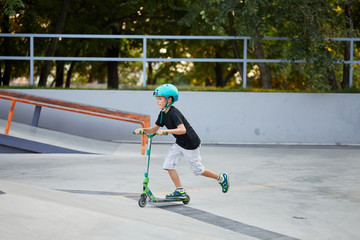 A boy on a scooter and in protective helmet do incredible stunts in skate park. Extreme jump. The concept of a healthy lifestyle and sports leisure