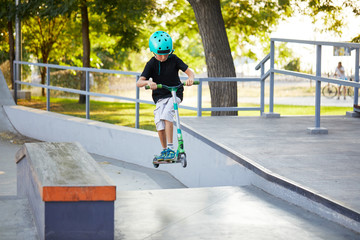 A boy on a scooter and in protective helmet do incredible stunts in skate park. Extreme jump. The concept of a healthy lifestyle and sports leisure © oes