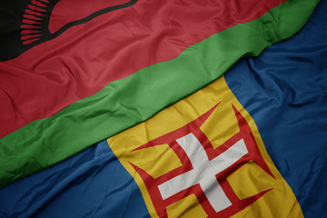waving colorful flag of madeira and national flag of malawi.