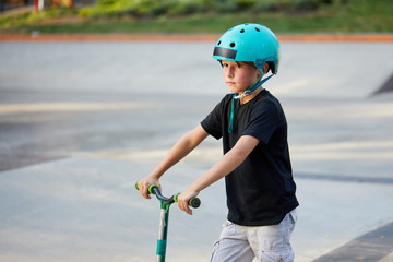 A boy on a scooter and in protective helmet do incredible stunts in skate park. Extreme jump. The concept of a healthy lifestyle and sports leisure © oes