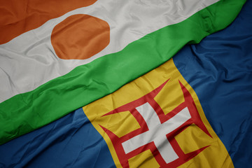 waving colorful flag of madeira and national flag of niger.