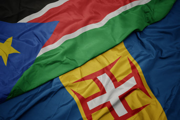 waving colorful flag of madeira and national flag of south sudan.