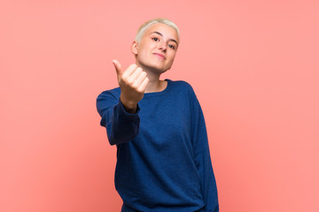 Teenager girl with white short hair over pink wall inviting to come with hand. Happy that you came
