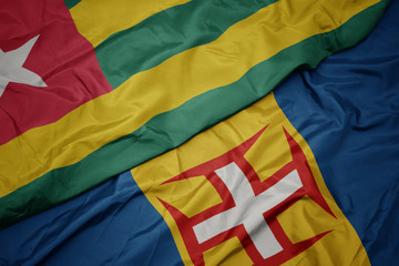 waving colorful flag of madeira and national flag of togo.