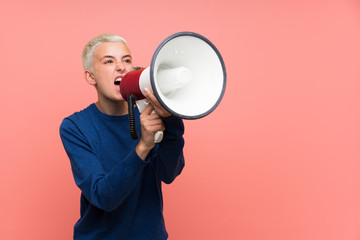 Teenager girl with white short hair over pink wall shouting through a megaphone