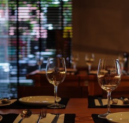 Restaurant table with empty wine glasses, forks, knives and black tablemat