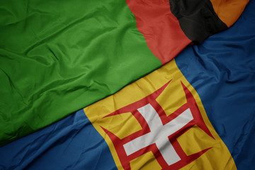 waving colorful flag of madeira and national flag of zambia