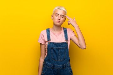 Teenager girl with overalls on yellow background with problems making suicide gesture