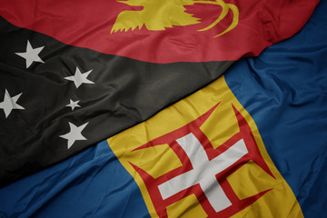 waving colorful flag of madeira and national flag of Papua New Guinea .