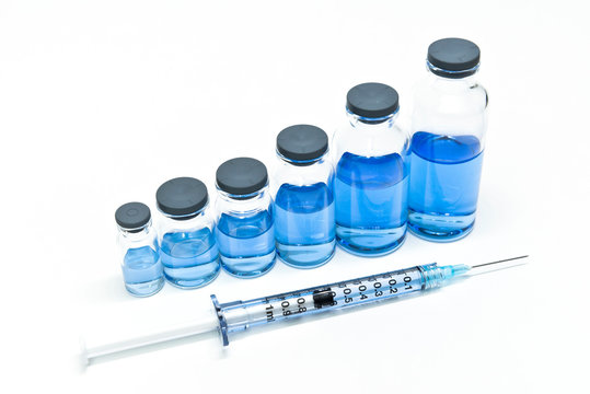 A seringe and serial volume up of medicine vials containing liquid medicine. Growth of pharmaceutical industry