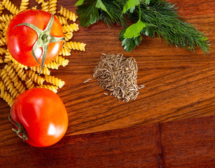 Pasta, two red tomatoes and spices on a cutting kitchen board. Ingredients for the sentence of food