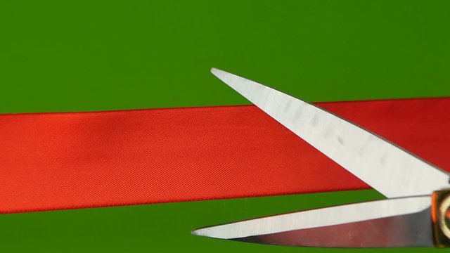 On a green background cut red ribbon. Slow motion