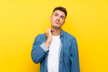 Young handsome man over isolated yellow background thinking an idea