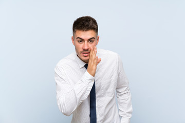 Handsome businessman over isolated blue background whispering something