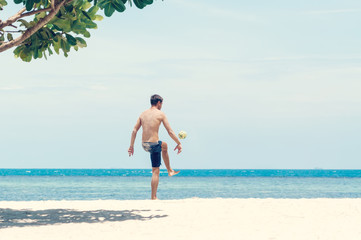 Energetic young man with athletic build plays ball on the beach