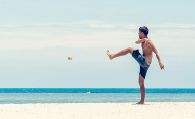 Energetic young man with athletic build plays ball on the beach