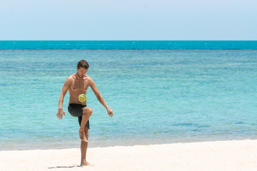 Energetic young man with athletic build plays ball on the beach