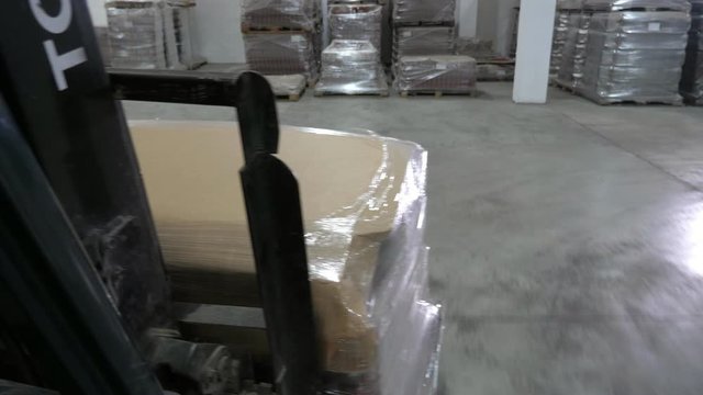 A forklift moving boxes with tomato tins in a modern plant to various piles 