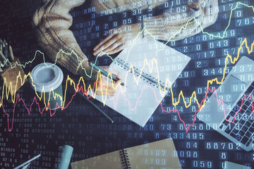 Forex graph on hand taking notes background. Concept of research. Double exposure