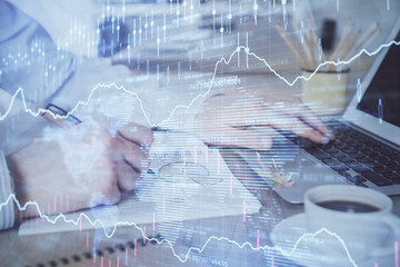 Multi exposure of stock market graph with man working on laptop on background. Concept of financial analysis.