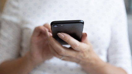 Senior woman holding smartphone using mobile app, close up view