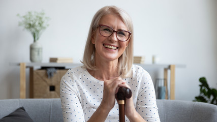 Happy old woman hold cane walking stick looking at camera