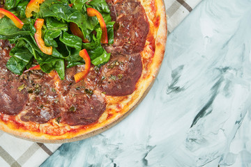 Italian juicy homemade pizza with vitello tonato veal and spinach leaves with red sauce and mozzarella on grey background.