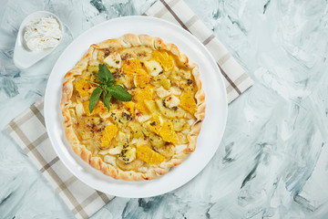 Homemade Hot fruit cake with orange, apples, pears and banana with cream on a gray background. Food at Dessert