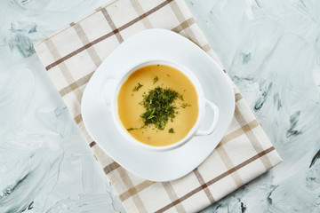 Portion of Creamy Cream Soup with Mushrooms in white bowl on cloth. Homemade cuisine. Gray background