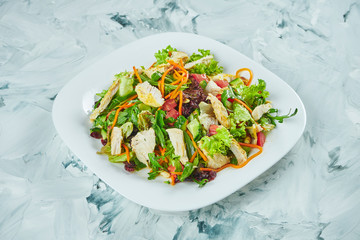 Portion of fresh and healthy salad with warm baked chicken on a gray background. Balanced food