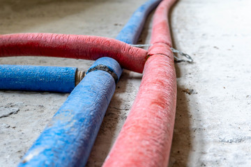 Underfloor heating system, red and blue plastic pipelines, collector case, background.