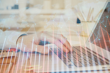 Double exposure of man's hands writing notes with laptop of stock market with forex graph background. Top View. Concept of research and trading.