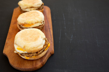 Homemade pork roll egg sandwich on a rustic wooden board on a black background, side view. Copy space.