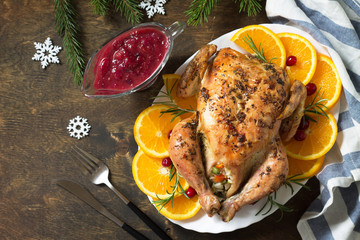 Concept of Christmas or New Year dinner roasted turkey stuffed with rice and Cranberry sauce on wooden table. Top view. Free space for your text.