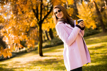 Fototapeta na wymiar Happy lovely young woman drinking outdoor coffee in autumn park