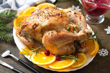 Concept of Christmas or New Year dinner roasted turkey stuffed with rice and Cranberry sauce on wooden table.
