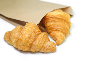 Fresh croissant in brown paper bag on white Background.Tasty buttery croissants.
