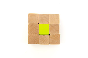 natural wooden blocks around green block with cup in the middle