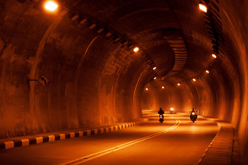 Riding motorcycles in a dark tunnel.