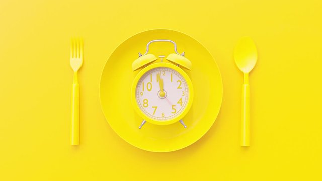 Yellow clock on yellow plate with fork and spoon background, Break time idea concept. The beginning of time 11.45 run fast to 12.00. Timelapse moving fast.