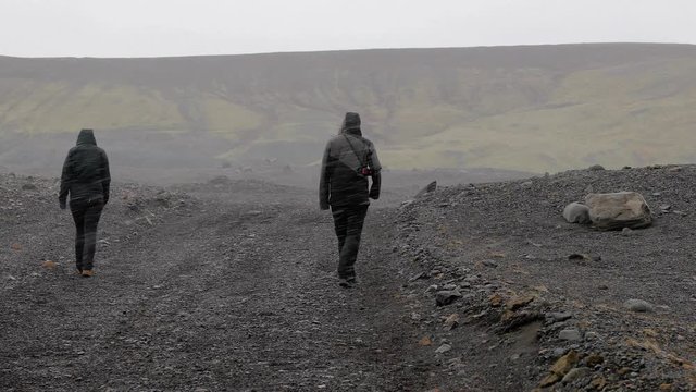 Walking in Iceland on a barren countryside landscape with falling snow and stormy wind